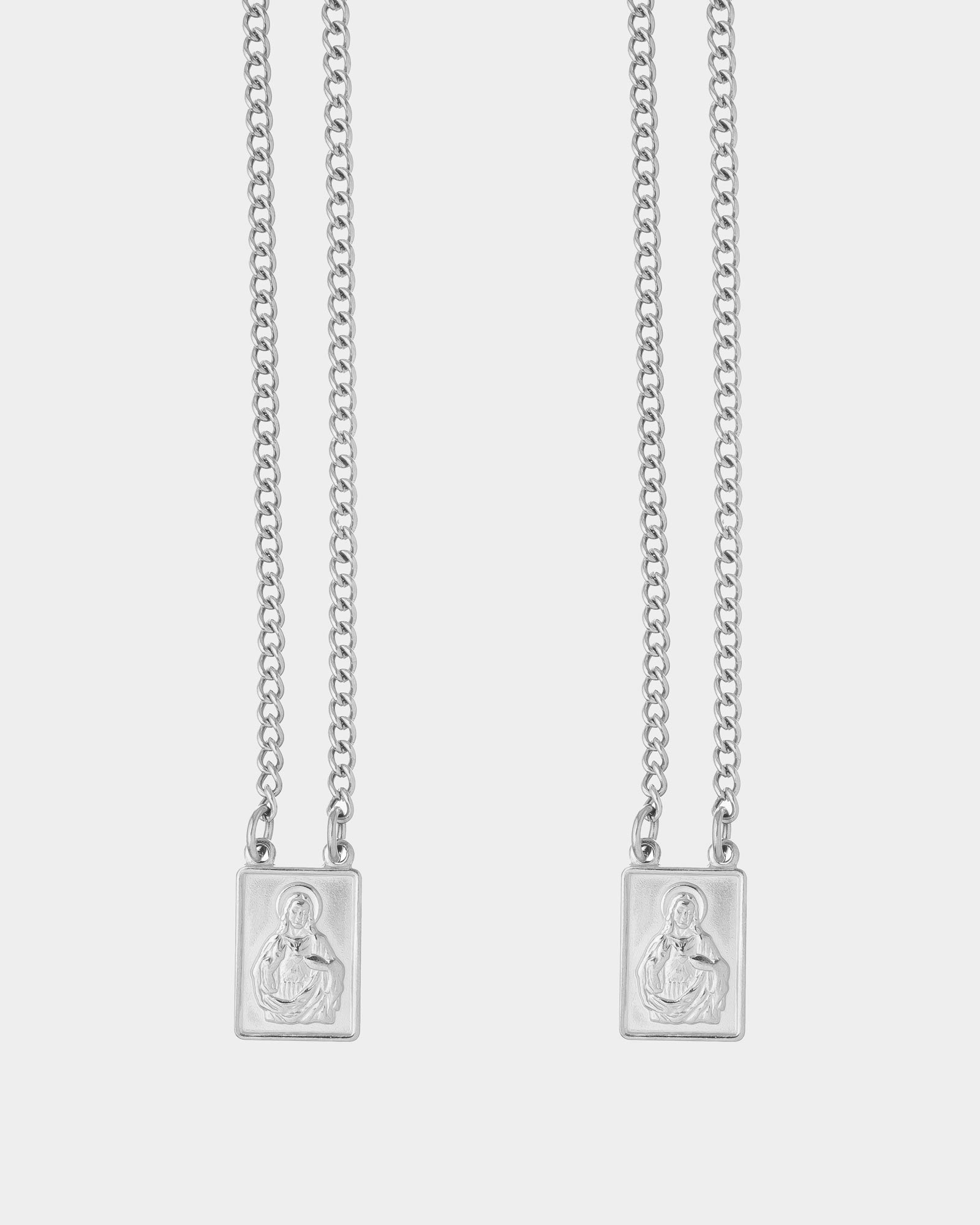 Silver - Two silver chain necklaces with rectangular pendants featuring an embossed figure, displayed against a light gray background.