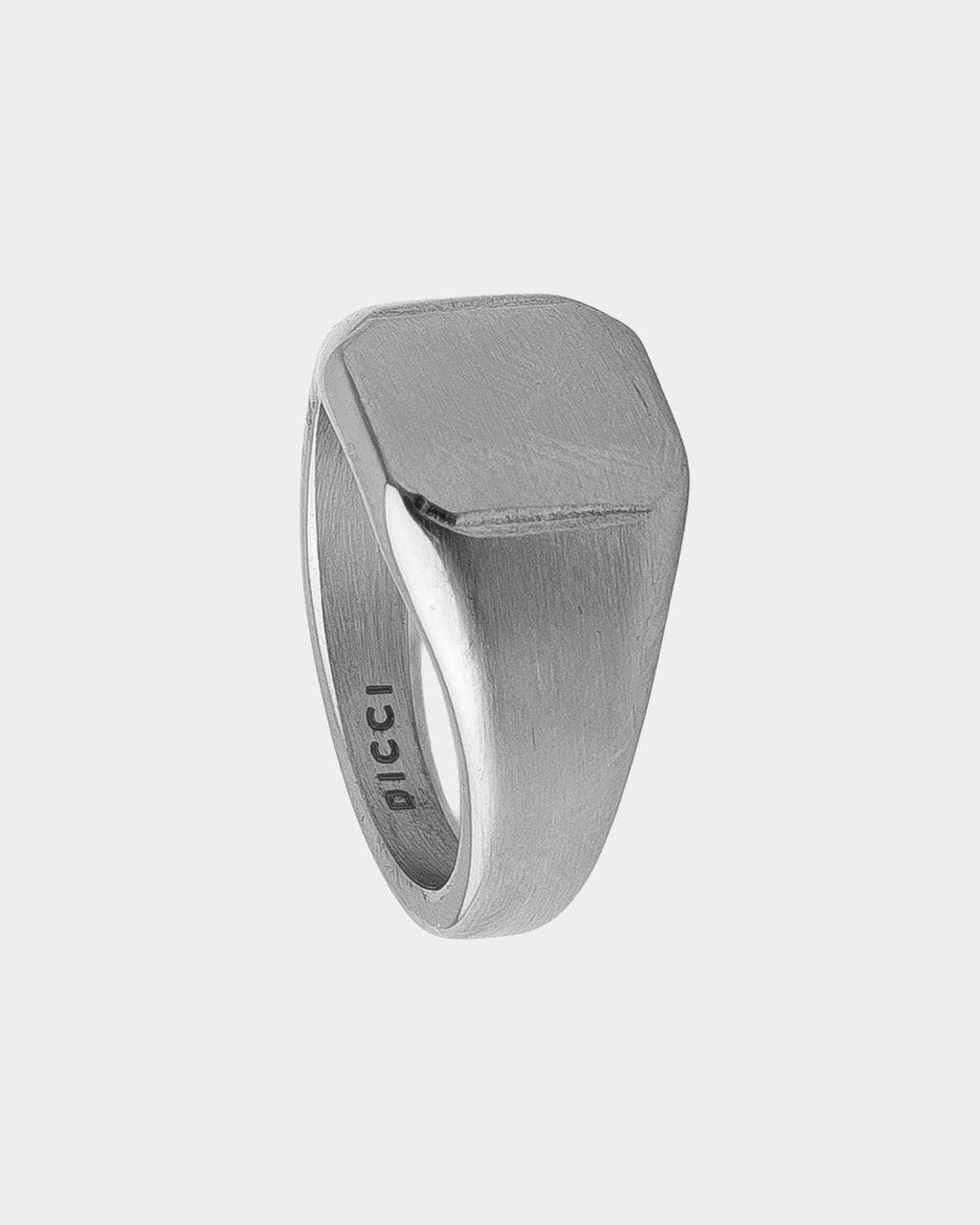 A silver signet ring with a brushed finish and the brand name 'DICCI' engraved on the inside band, shown on a light gray background.