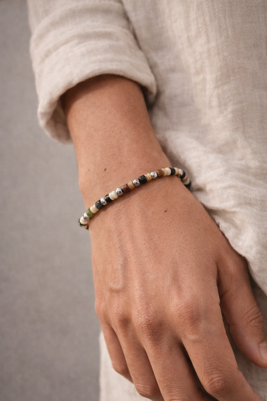 Close-up of a hand wearing a beaded bracelet on a neutral background - Nerano Bracelet
