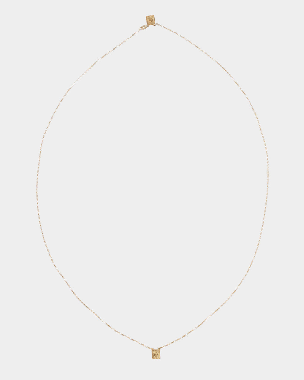 Golden - A delicate gold chain necklace with a small rectangular gold pendant, displayed against a solid light gray background.