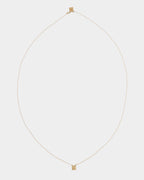 Golden - A delicate gold chain necklace with a small rectangular gold pendant, displayed against a solid light gray background.