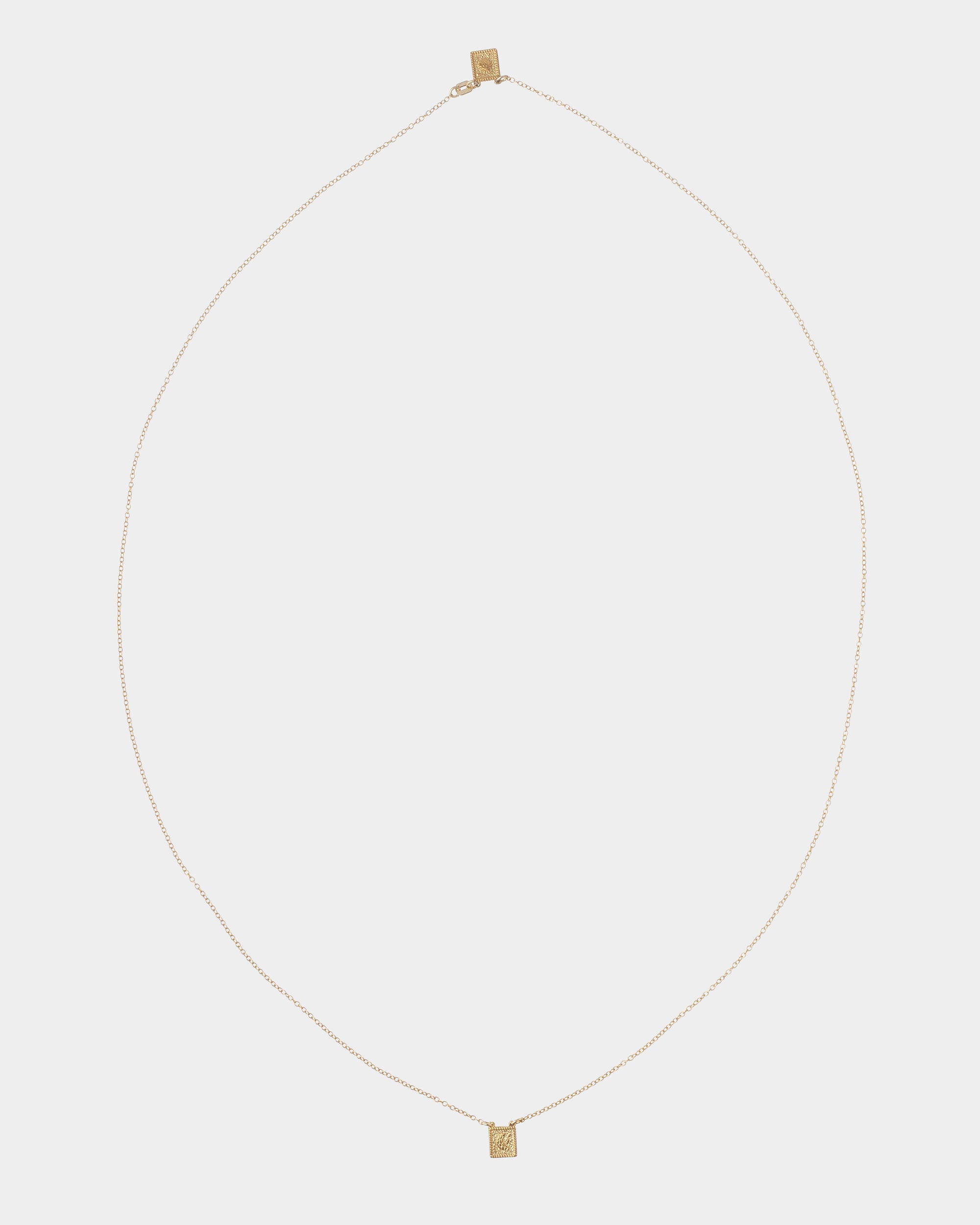 Golden - A delicate gold chain necklace with a small rectangular gold pendant, displayed against a solid light gray background.