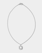 Silver necklace with a sun pendant on a light gray background