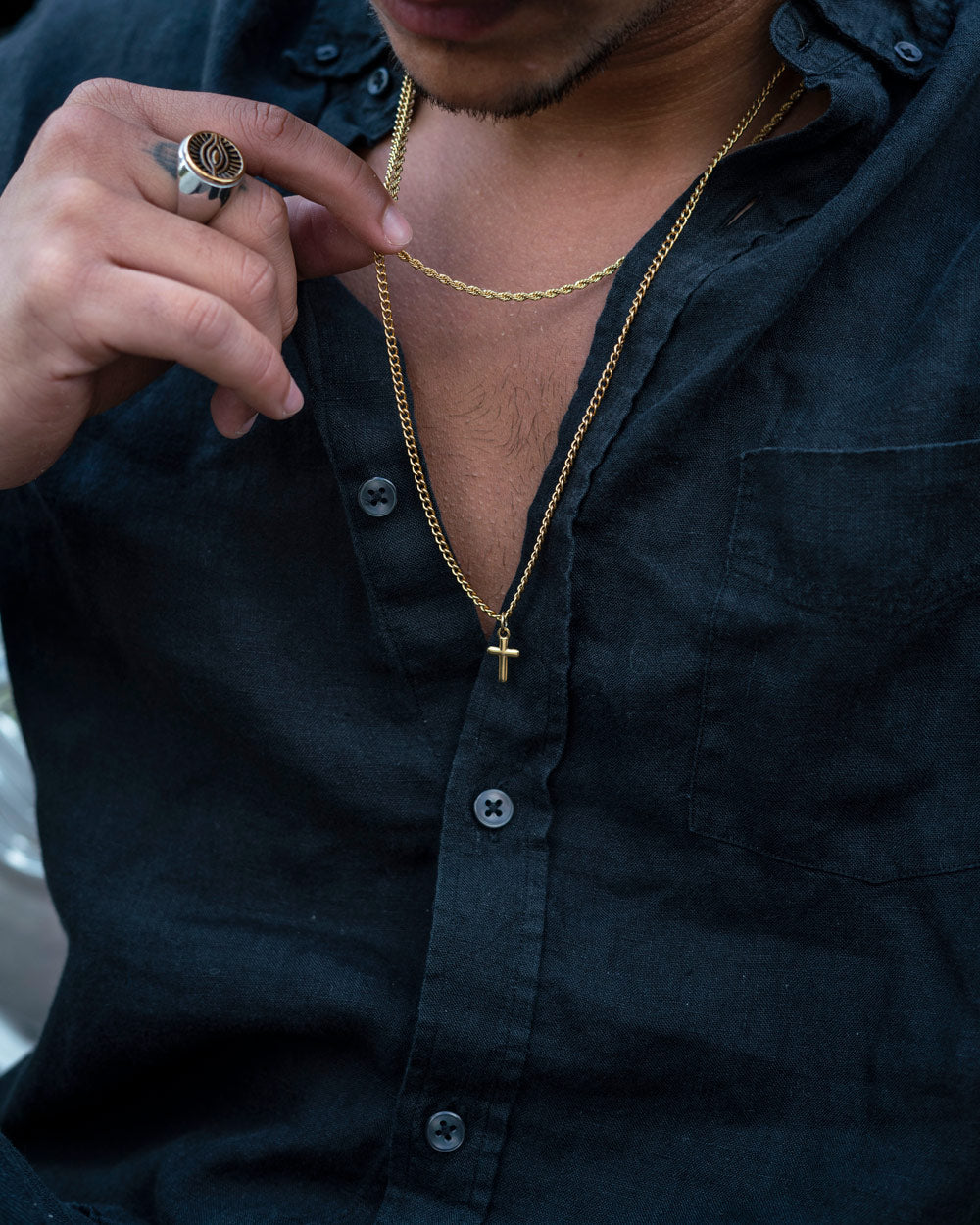 Man wearing Caprera Golden Necklace with cross pendant and black shirt