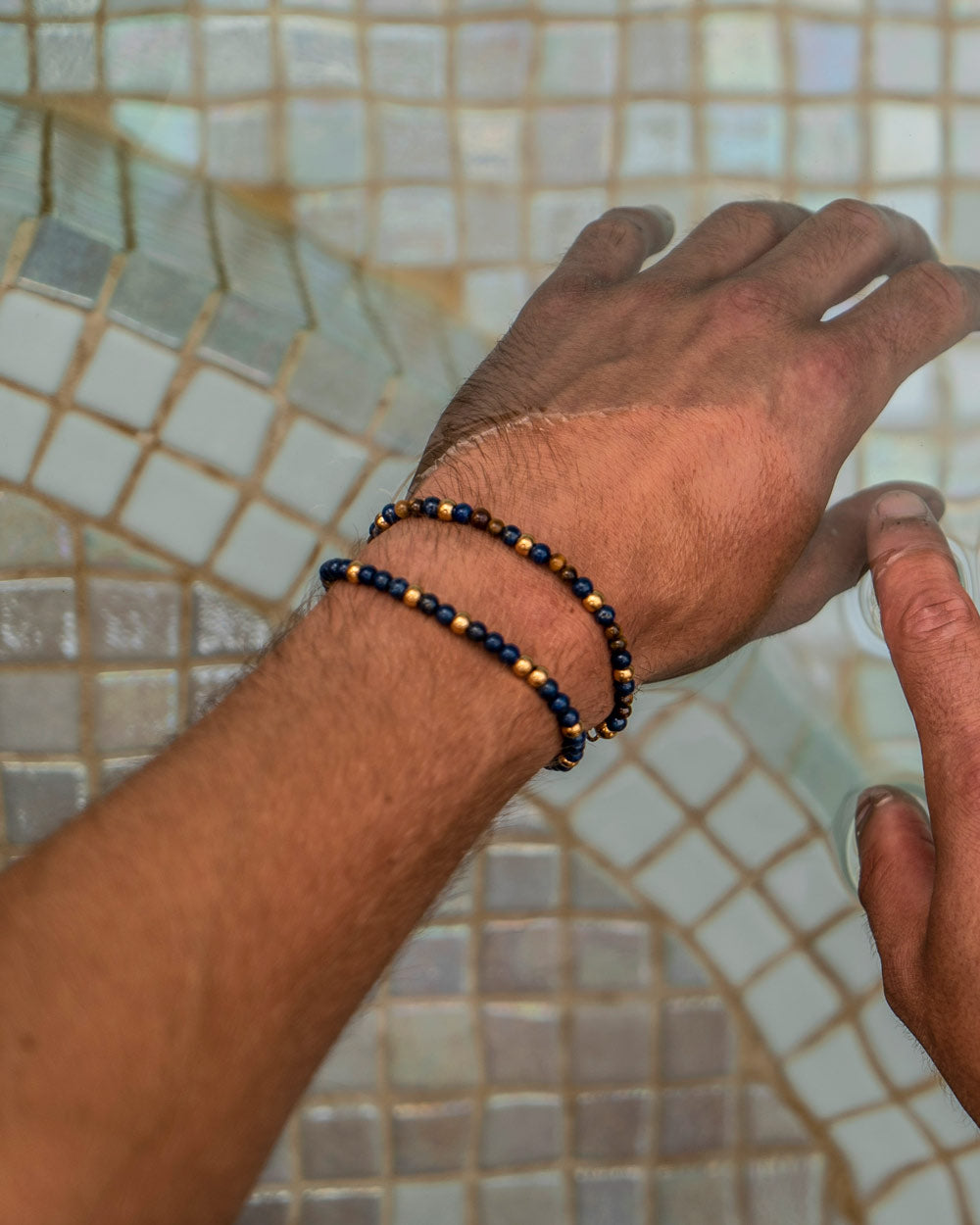 Navagio - Pulseira de pedras naturais Navagio no pulso do modelo - Pedras lápis-lazúli e olho de tigre com detalhes em aço inoxidável dourado - Pulseiras de Pedras Naturais - Joias Unissexo Online - Dicci