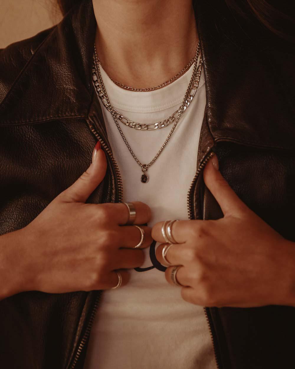 Silver Figaro Chain 3x1 Necklace 6mm layered with other silver chains on person wearing white shirt and brown leather jacket